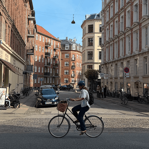 A cyclist riding along a cobbled street in Copenhagen